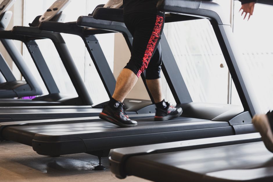 Een moderne loopband in een thuisfitnessomgeving met een persoon die traint.